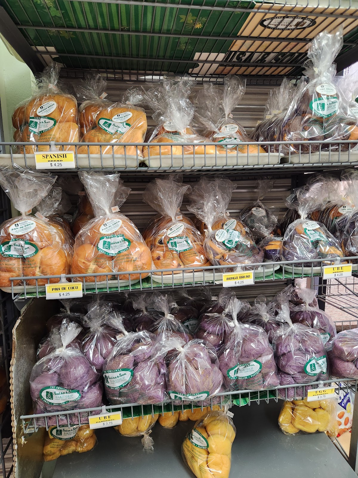 Ube pandesal, egg pandesal and Spanish bread on the shelves with yellow price tags